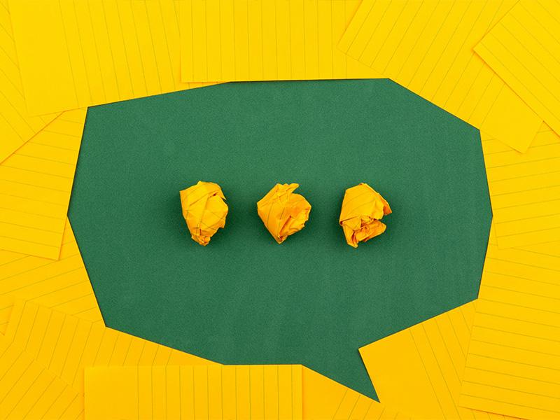 Yellow pieces of paper are used to depict a speech bubble and 3 dots in the centre