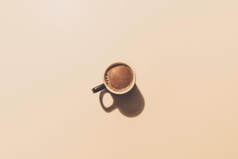 A mug of coffee in the centre of a plain beige background
